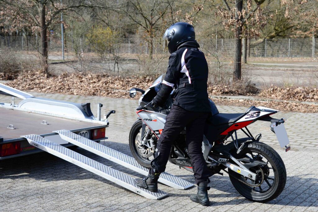 Motorrad Tandem Anhänger Motorradfahrer schiebt sein Bike hoch