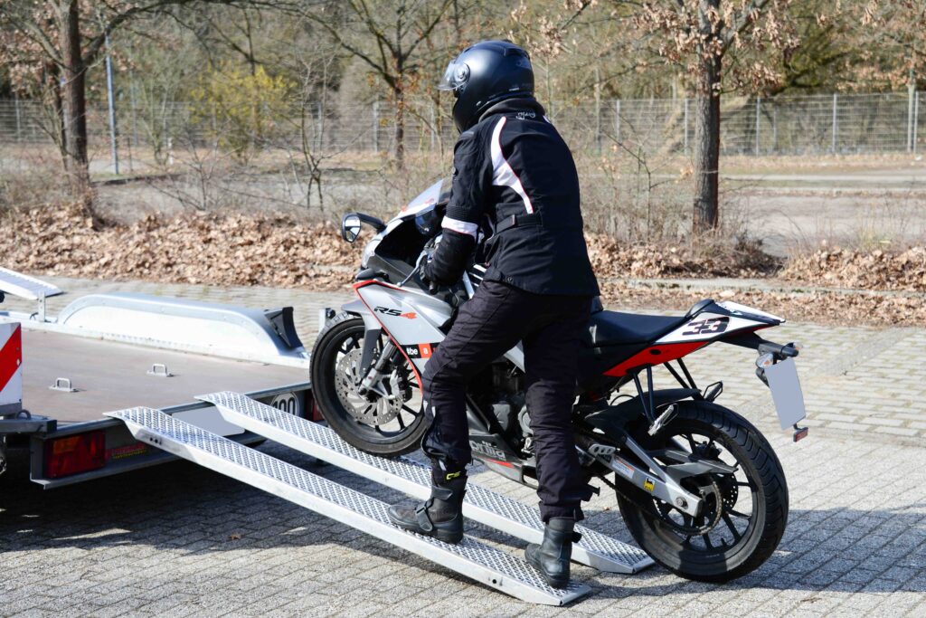 Motorrad Tandem Anhänger Motorradfahrer schiebt sein Bike hoch