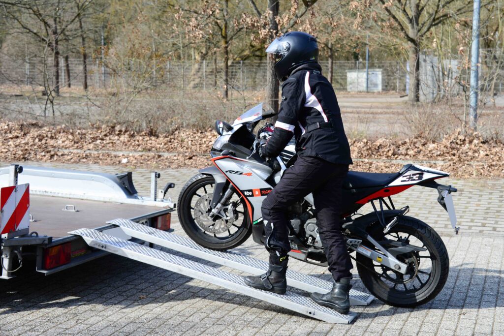 Motorrad Tandem Anhänger Motorradfahrer schiebt sein Bike hoch